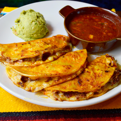 Birria tacos with cilantro, onion, lime, and consommé