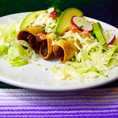 Golden chicken flautas with lettuce, cheese, avocado, rice, and beans